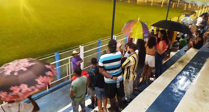 Imagem Do Dia:  Torcida precisa de guardas chuvas e sombrinhas debaixo da cobertura das arquibancadas do Estádio Municipal em Mantena 